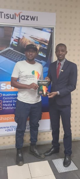 An author receiving his finished book from TisuMazwi in front of the studio services banner.